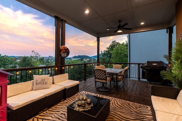 deck at dusk featuring grilling area, ceiling fan, and outdoor lounge area