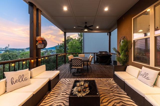 deck at dusk featuring ceiling fan, a grill, and outdoor lounge area