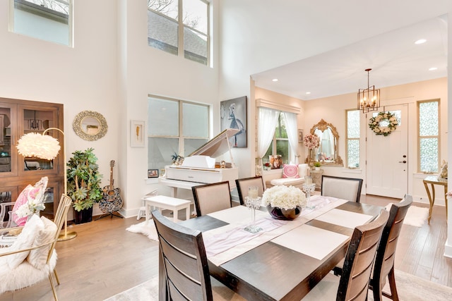 dining room with a towering ceiling, light hardwood / wood-style flooring, and a notable chandelier