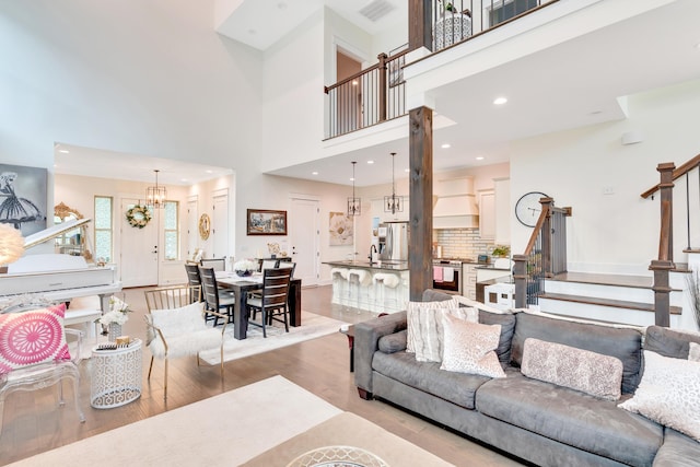 living room with sink, light hardwood / wood-style floors, a high ceiling, and a notable chandelier