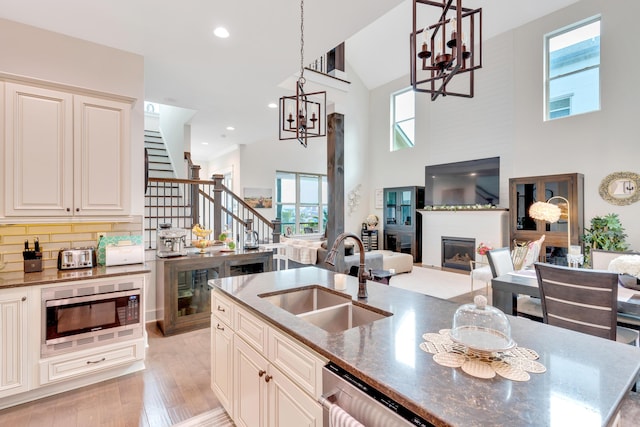 kitchen with appliances with stainless steel finishes, decorative light fixtures, sink, backsplash, and a notable chandelier