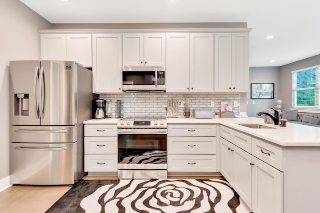 kitchen featuring backsplash, sink, light hardwood / wood-style flooring, appliances with stainless steel finishes, and white cabinets