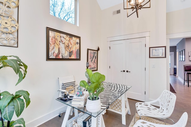 office space featuring dark wood-type flooring, a high ceiling, and a notable chandelier