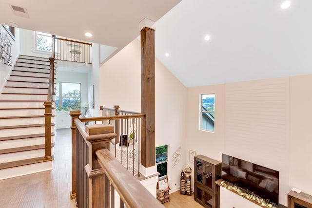 stairway with high vaulted ceiling and wood-type flooring