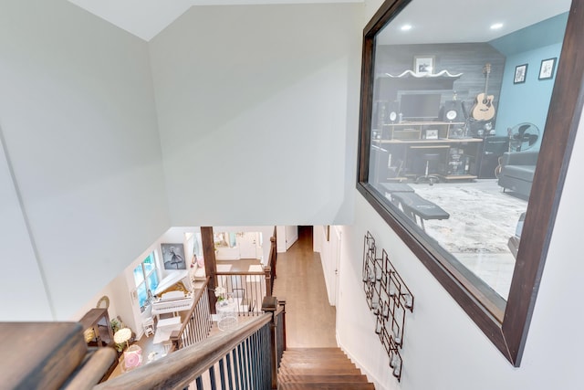 stairway with lofted ceiling and hardwood / wood-style floors