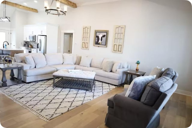 living room with sink, beamed ceiling, a chandelier, and hardwood / wood-style flooring