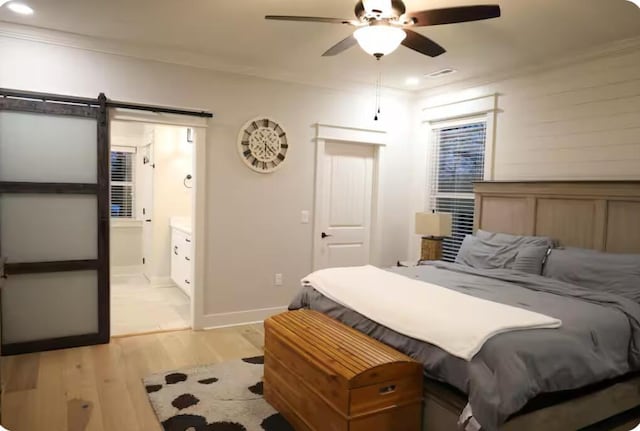 bedroom featuring a barn door, ceiling fan, ornamental molding, and light wood-type flooring