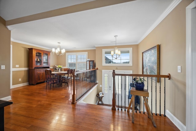 interior space with dark wood-type flooring, an inviting chandelier, and ornamental molding