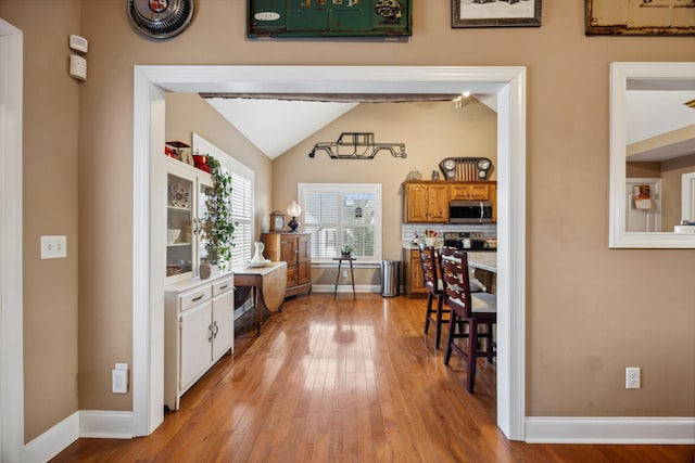 dining space featuring light wood-type flooring and vaulted ceiling