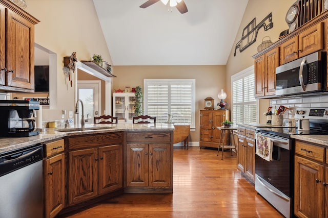 kitchen featuring light stone counters, stainless steel appliances, ceiling fan, sink, and light hardwood / wood-style floors