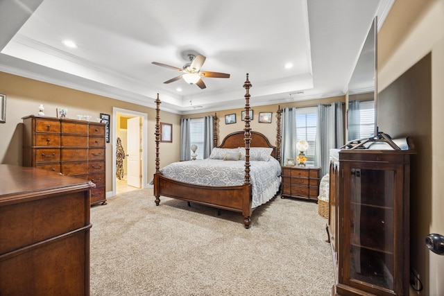 bedroom featuring connected bathroom, ceiling fan, a tray ceiling, light carpet, and ornamental molding