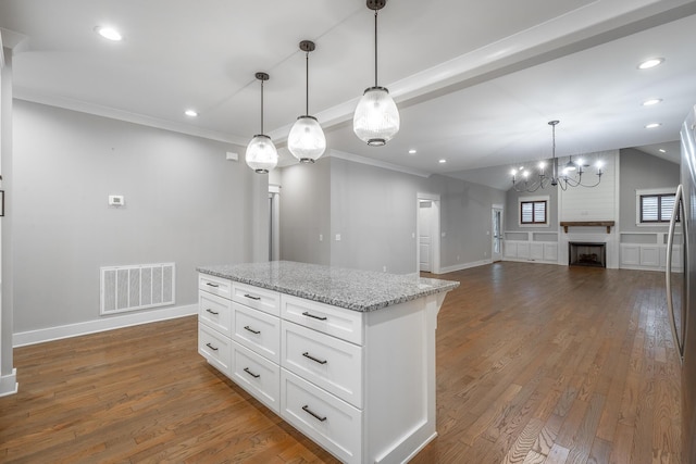 kitchen with white cabinets, pendant lighting, a large fireplace, and light stone counters