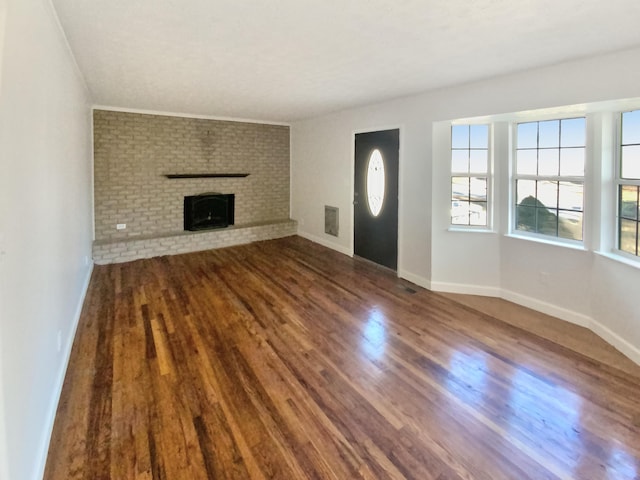 unfurnished living room featuring hardwood / wood-style flooring and a brick fireplace