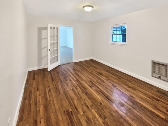 empty room featuring french doors and dark wood-type flooring