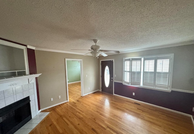 unfurnished living room featuring ceiling fan, light wood-type flooring, a textured ceiling, and a tile fireplace