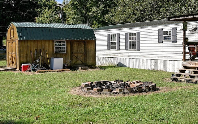 view of outbuilding with a yard and an outdoor fire pit