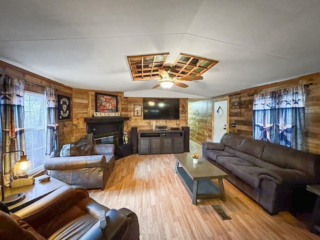 living room featuring lofted ceiling, light hardwood / wood-style flooring, ceiling fan, and wood walls