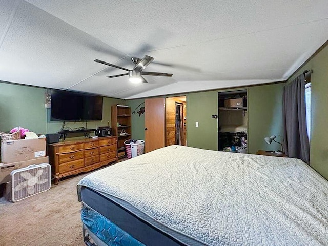 bedroom featuring vaulted ceiling, carpet floors, ceiling fan, and a textured ceiling