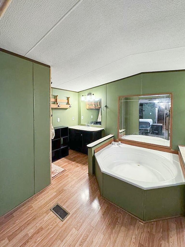 bathroom featuring a tub to relax in, hardwood / wood-style floors, vanity, and a textured ceiling