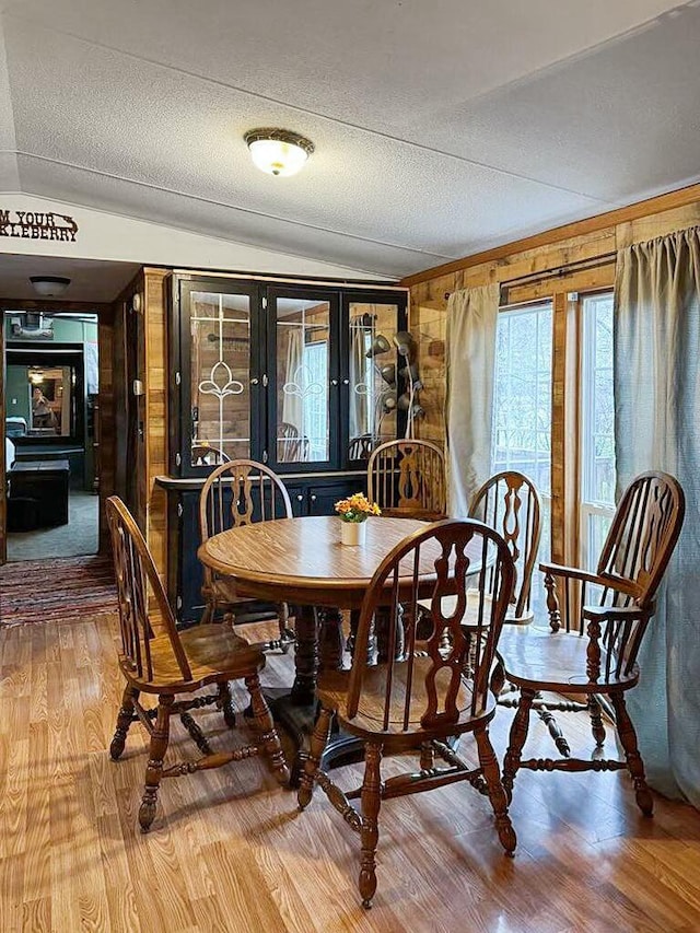 dining space with lofted ceiling, wood-type flooring, french doors, and a textured ceiling