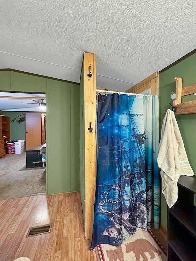 bathroom featuring hardwood / wood-style floors, ornamental molding, and a textured ceiling