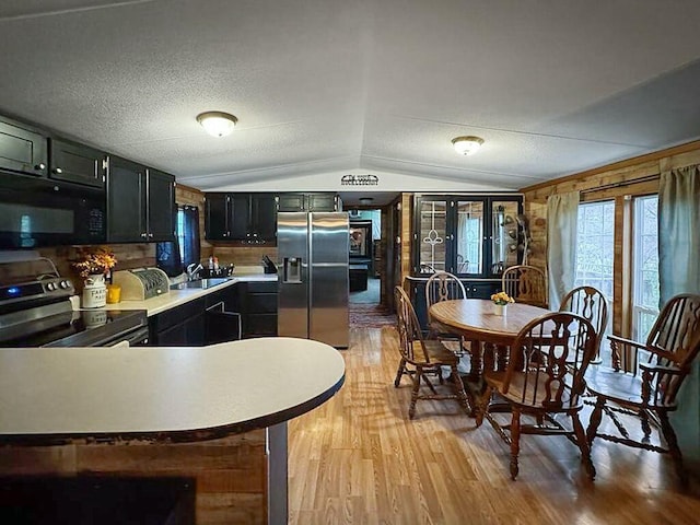 kitchen with lofted ceiling, sink, light hardwood / wood-style flooring, a textured ceiling, and appliances with stainless steel finishes