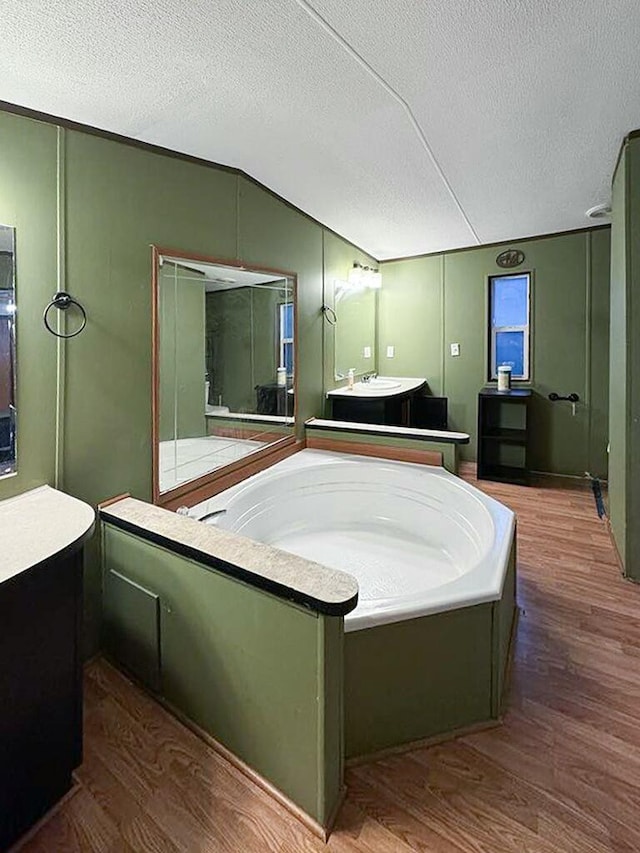 bathroom featuring lofted ceiling, hardwood / wood-style floors, a textured ceiling, and a bathing tub