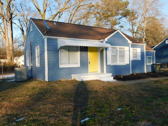 view of front of house with central AC and a front lawn