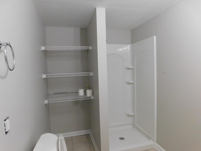 bathroom featuring tile patterned floors, a shower, and toilet