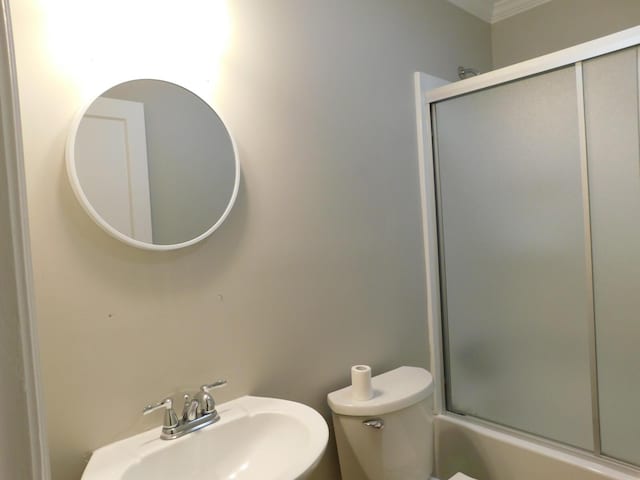 full bathroom featuring shower / bath combination with glass door, sink, and toilet