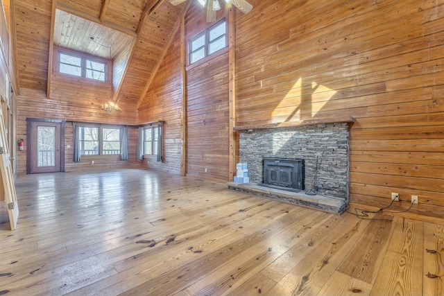 unfurnished living room with wooden ceiling, ceiling fan, high vaulted ceiling, a wood stove, and beam ceiling