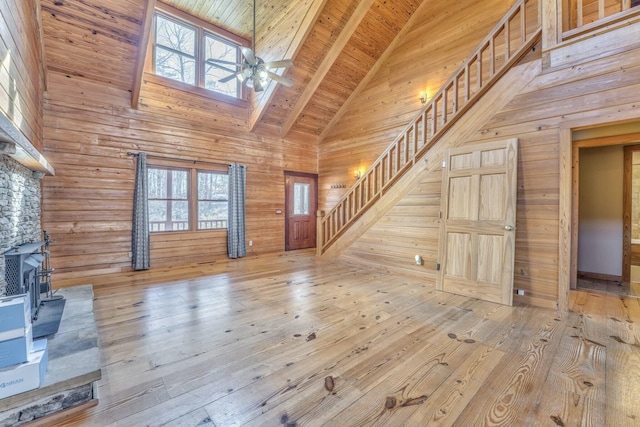 unfurnished living room with wood ceiling, light hardwood / wood-style floors, high vaulted ceiling, a wood stove, and beam ceiling