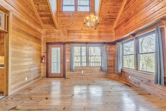 interior space with wooden ceiling, wood walls, a chandelier, and light hardwood / wood-style floors