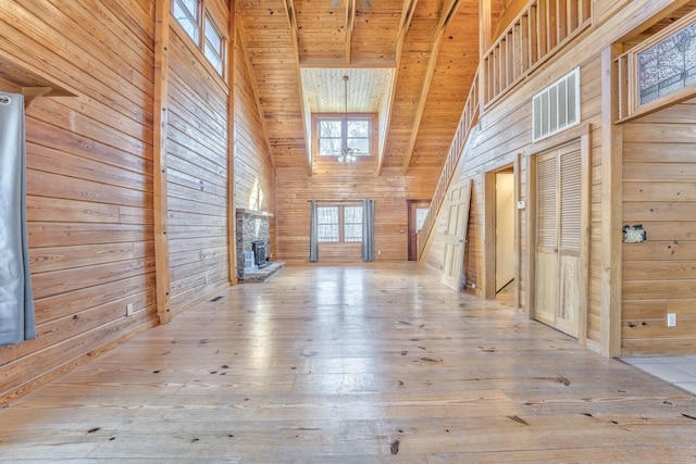 bonus room with high vaulted ceiling, wooden walls, a fireplace, and light wood-type flooring