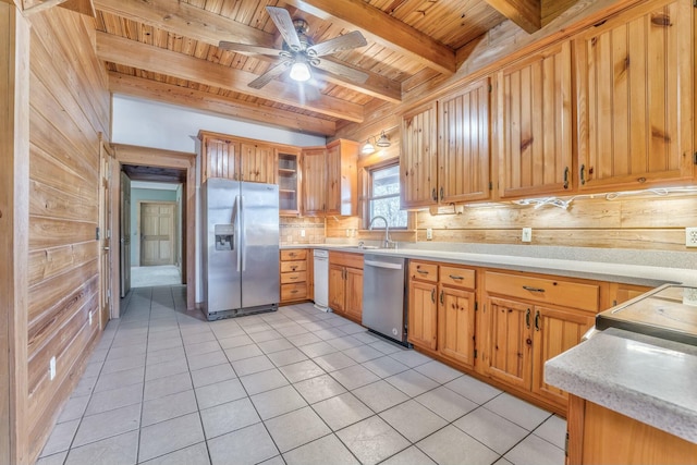 kitchen with stainless steel appliances, wooden ceiling, beamed ceiling, light tile patterned flooring, and wood walls