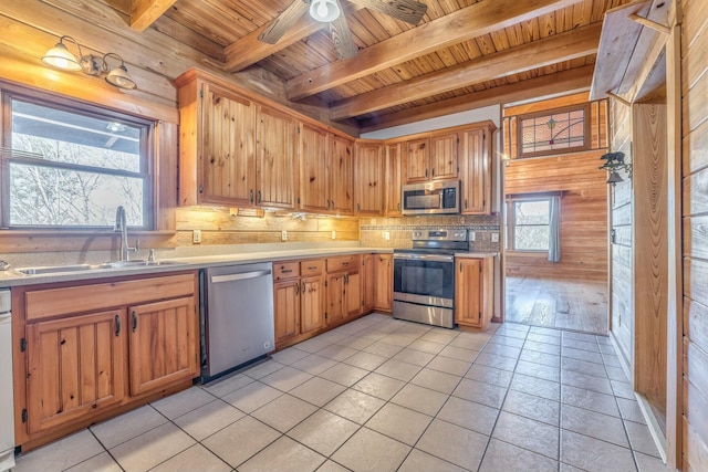 kitchen featuring sink, light tile patterned flooring, wood walls, and appliances with stainless steel finishes