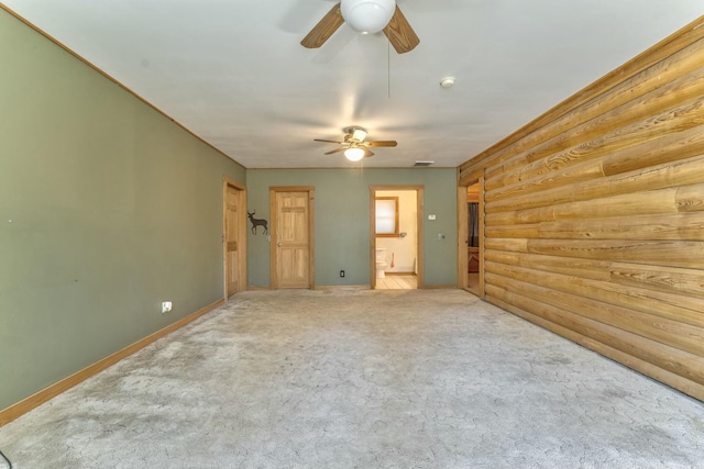 carpeted spare room with rustic walls and ceiling fan