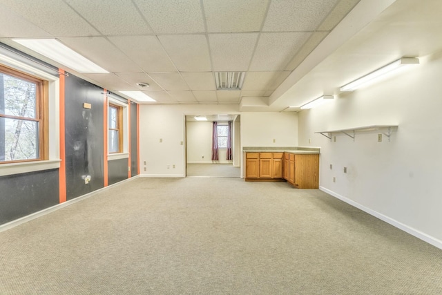 basement featuring a paneled ceiling and light colored carpet