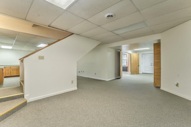 basement with a paneled ceiling and light carpet