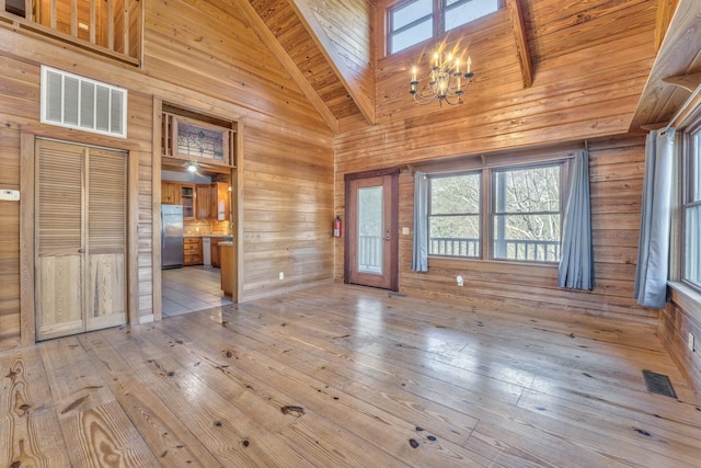 interior space featuring wooden walls, beamed ceiling, high vaulted ceiling, a chandelier, and wood ceiling