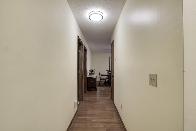 hall with wood-type flooring and a textured ceiling