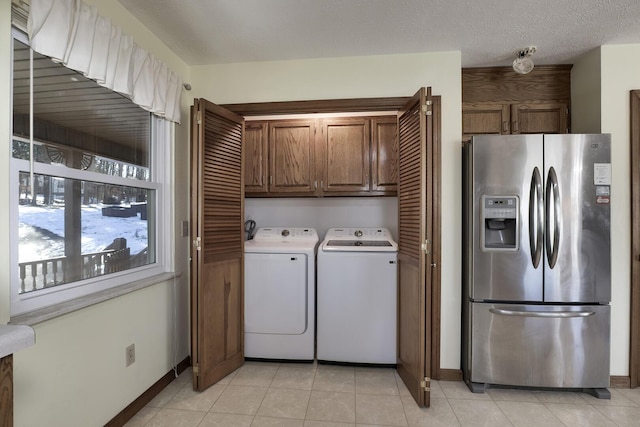 laundry area featuring cabinets, washing machine and dryer, light tile patterned flooring, and a textured ceiling