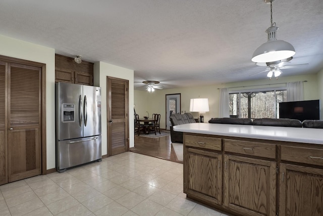 kitchen with stainless steel refrigerator with ice dispenser, ceiling fan, hanging light fixtures, and a textured ceiling