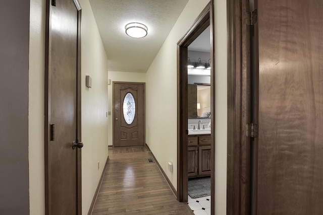 doorway with sink, hardwood / wood-style floors, and a textured ceiling