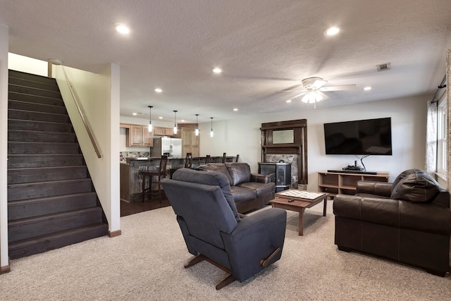 carpeted living room with ceiling fan and a textured ceiling