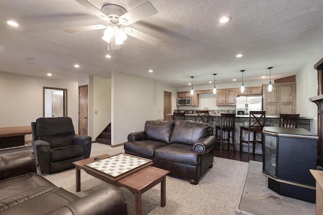 living room featuring ceiling fan, a textured ceiling, and light hardwood / wood-style flooring