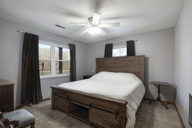 bedroom featuring light carpet, a textured ceiling, and ceiling fan