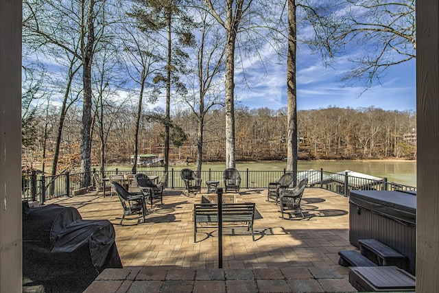 view of patio with a hot tub and a water view