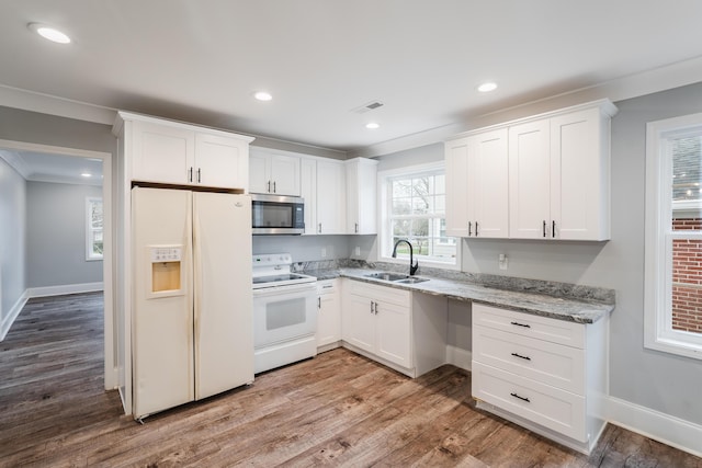 kitchen with white cabinetry, sink, light stone counters, hardwood / wood-style floors, and white appliances