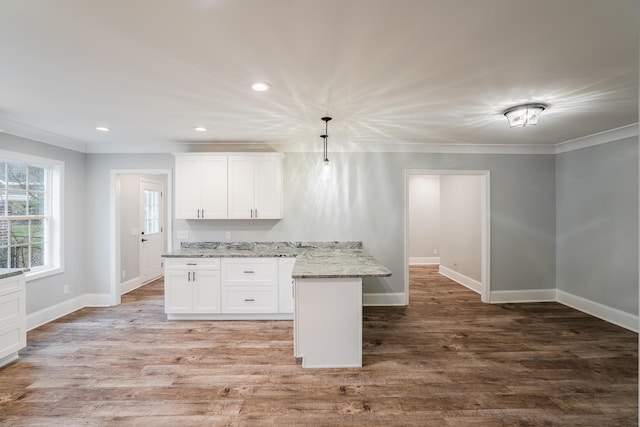 kitchen with white cabinetry, hanging light fixtures, light stone counters, and ornamental molding